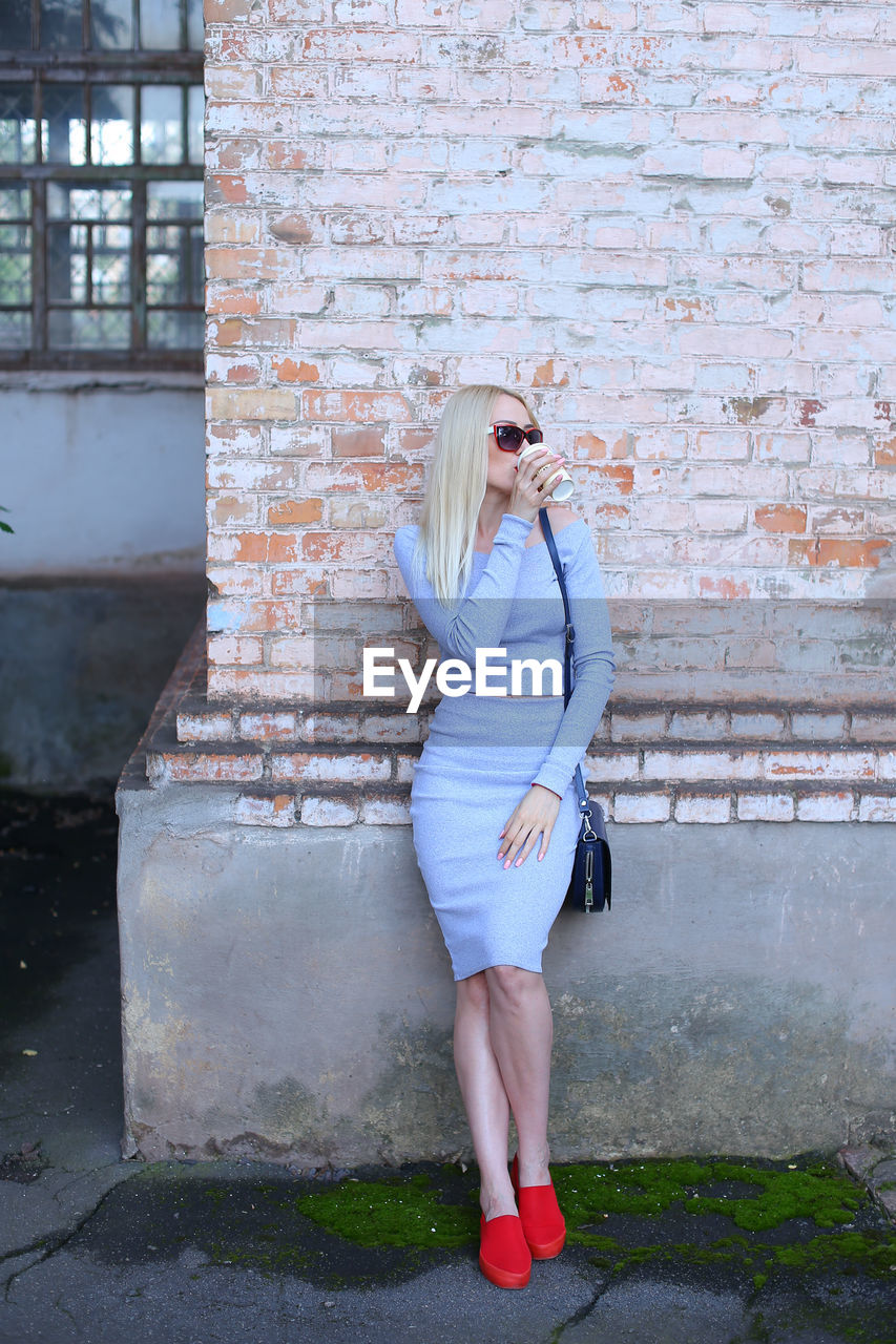 Full length of woman standing against brick wall