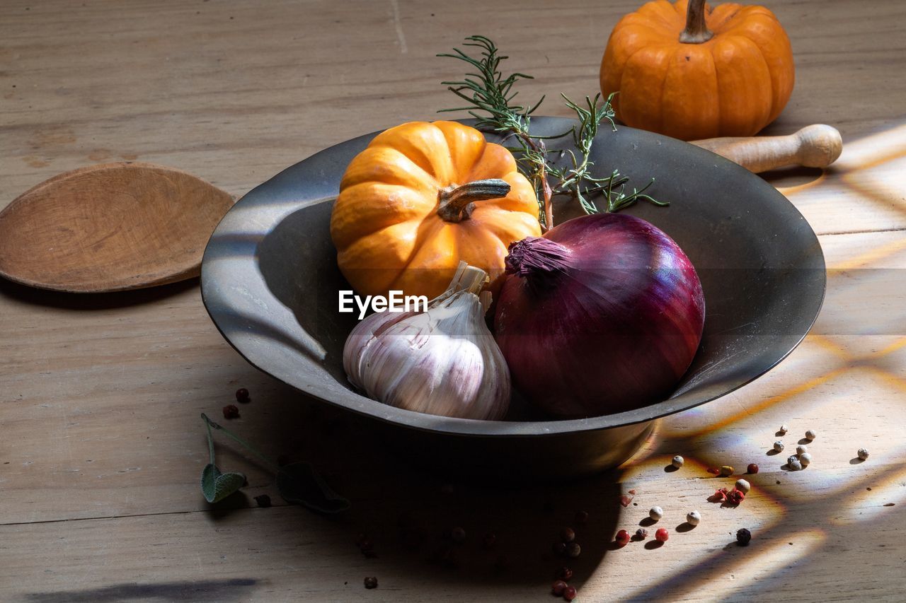 High angle view of pumpkins garlic and onion on table