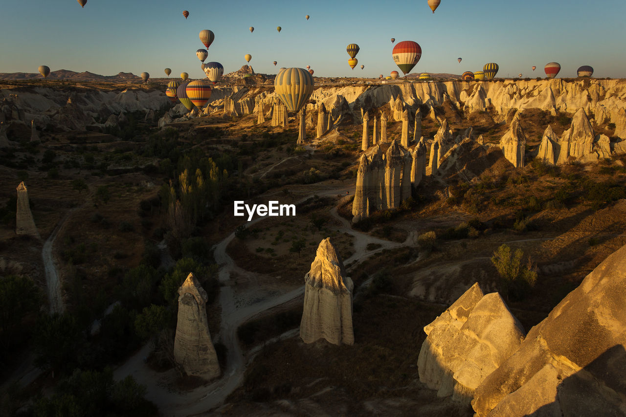 Hot air balloons flying over rocky landscape during sunny day