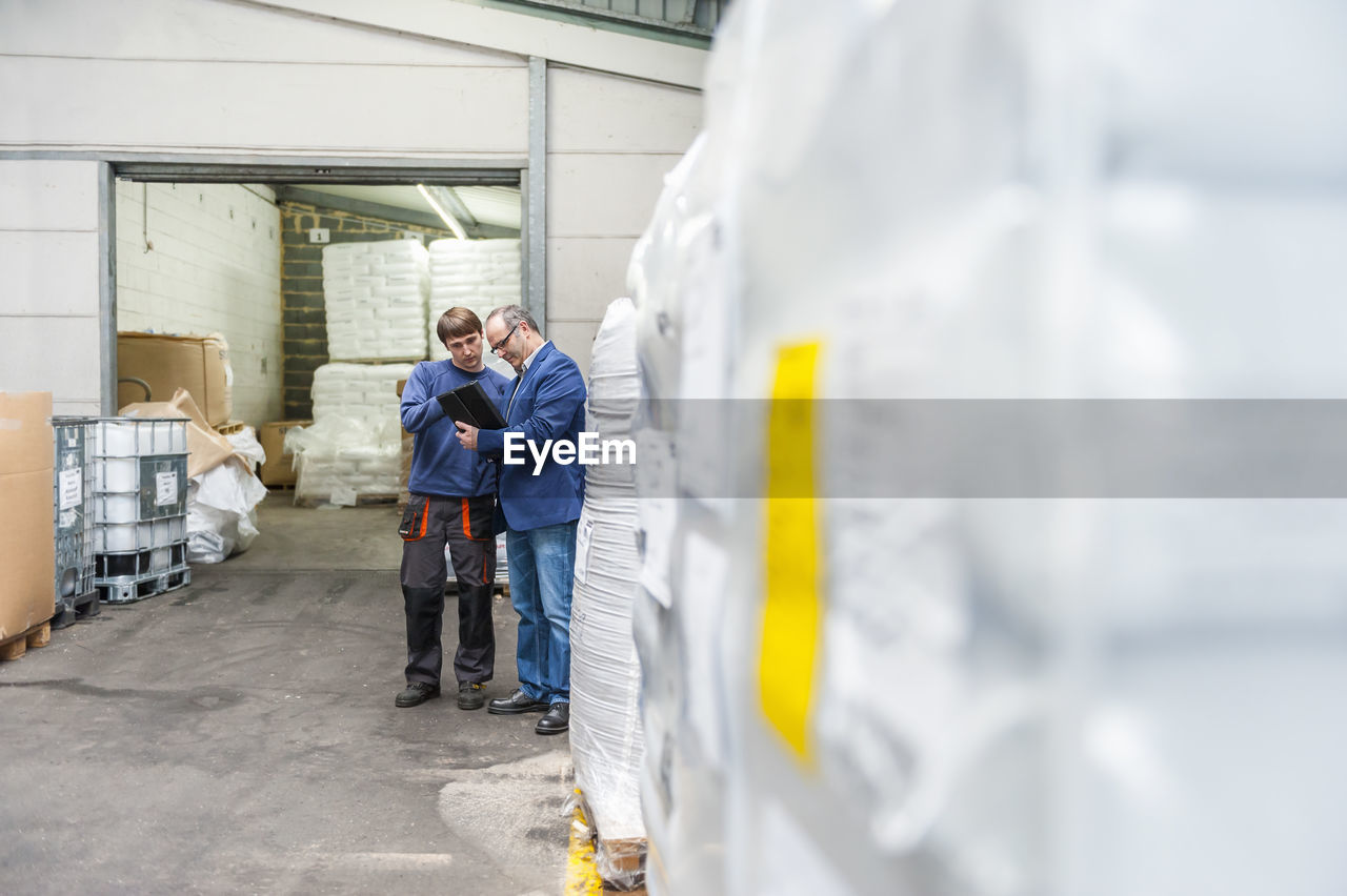 Manager and worker in storage of plastics factory checking products