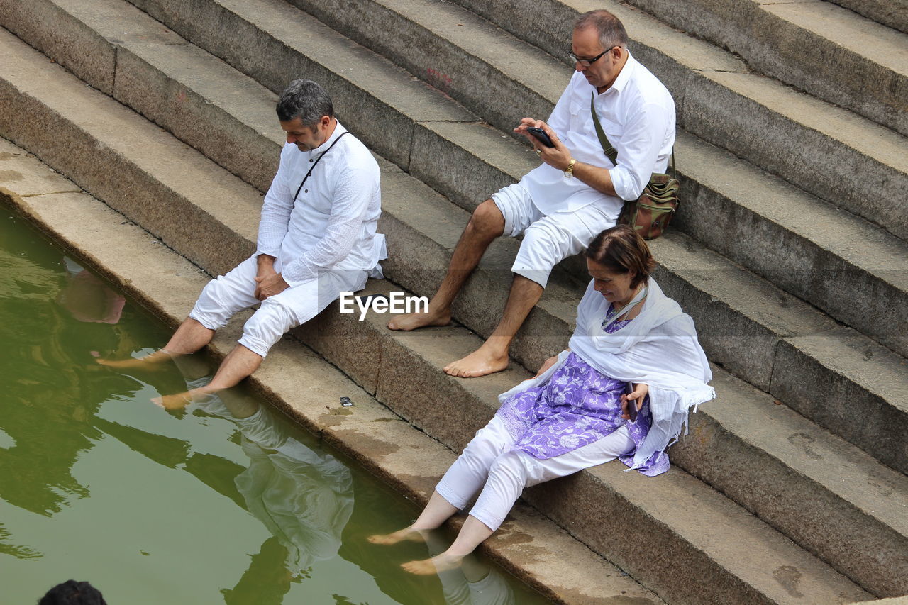 People sitting on steps at riverbank