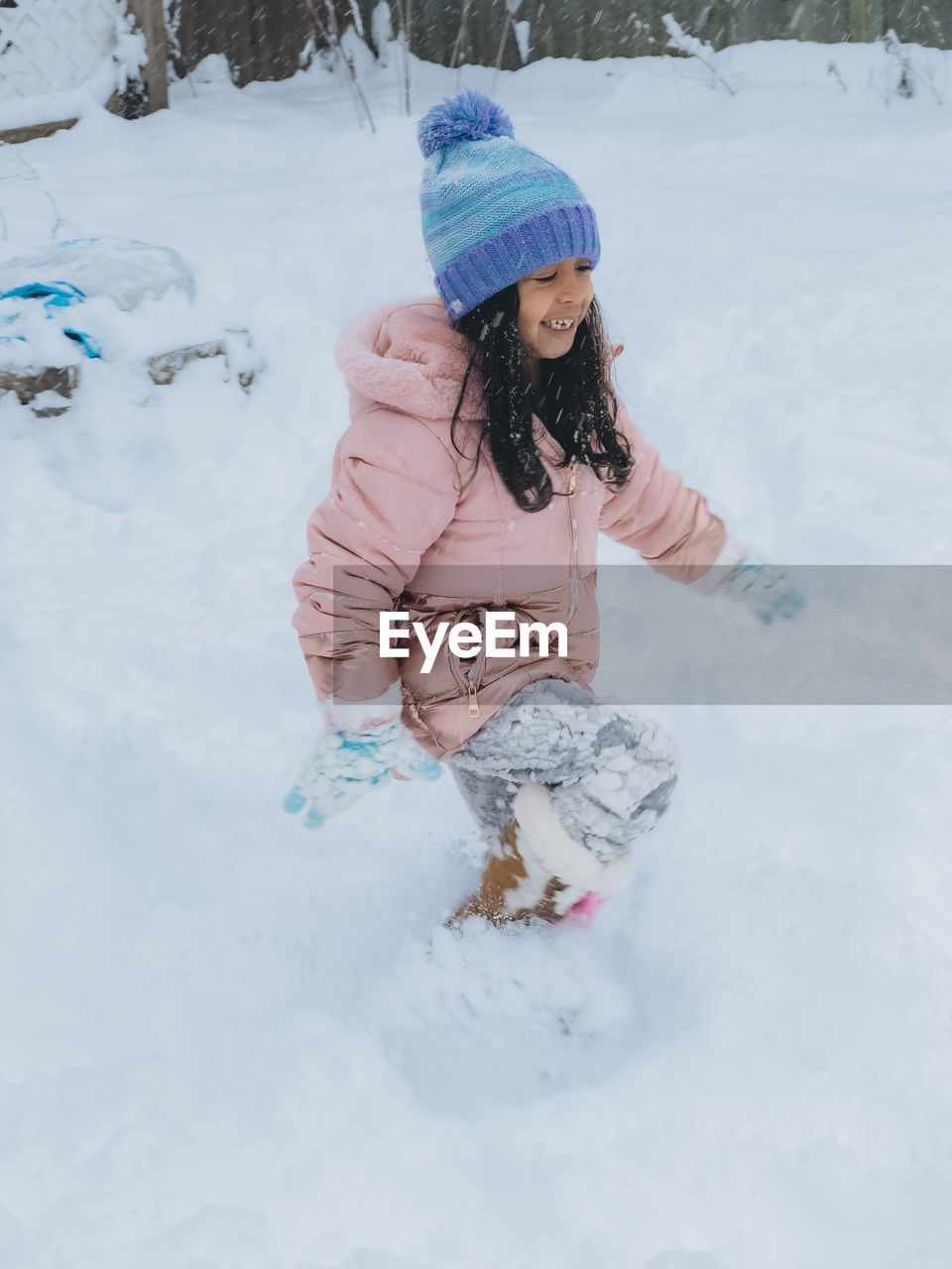 Diverse mixed race pre school toddler girl outdoors in winter playing with snow 