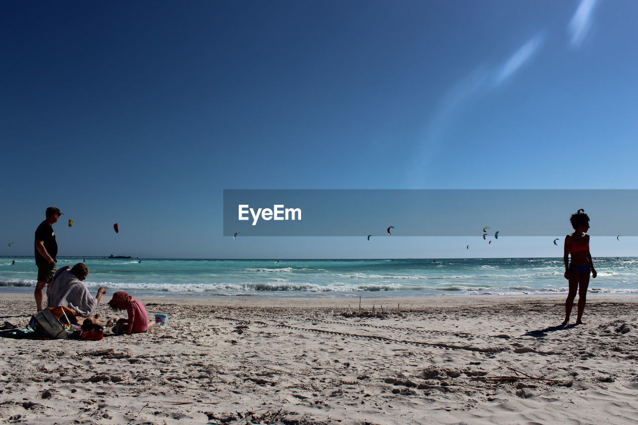 PEOPLE ON BEACH AGAINST BLUE SKY