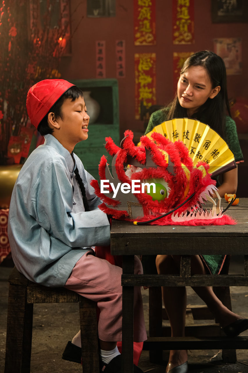 two people, women, adult, smiling, food and drink, men, happiness, emotion, child, red, female, food, childhood, celebration, togetherness, lifestyles, sitting, family, clothing, cheerful, positive emotion, holding, architecture, young adult, holiday, hat, business, nature, love
