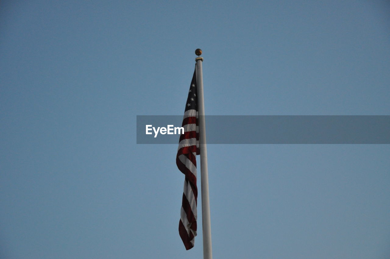 Low angle view of flag against clear blue sky