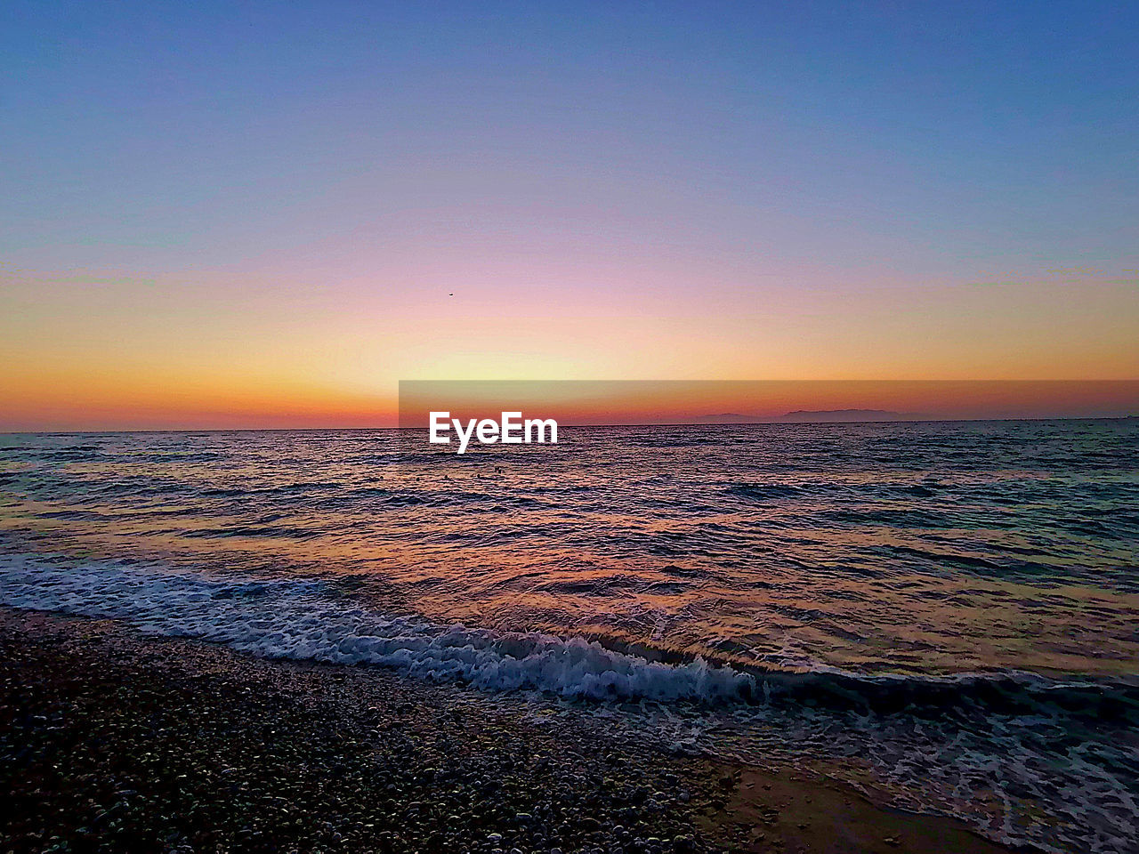 SCENIC VIEW OF BEACH AGAINST SKY DURING SUNSET