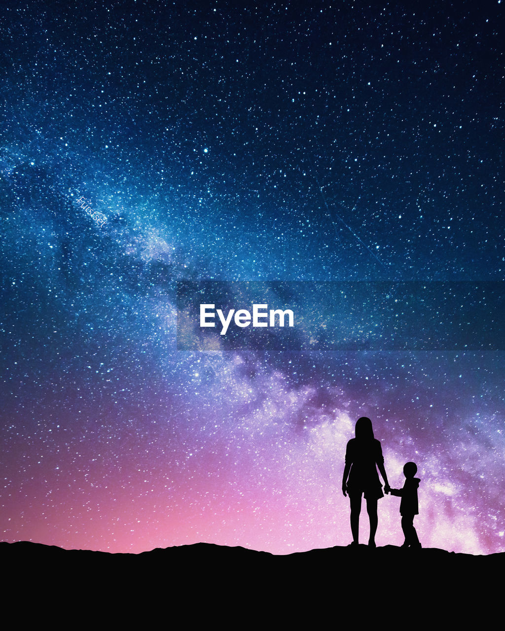 Silhouette mother and son standing on field against starry sky at night