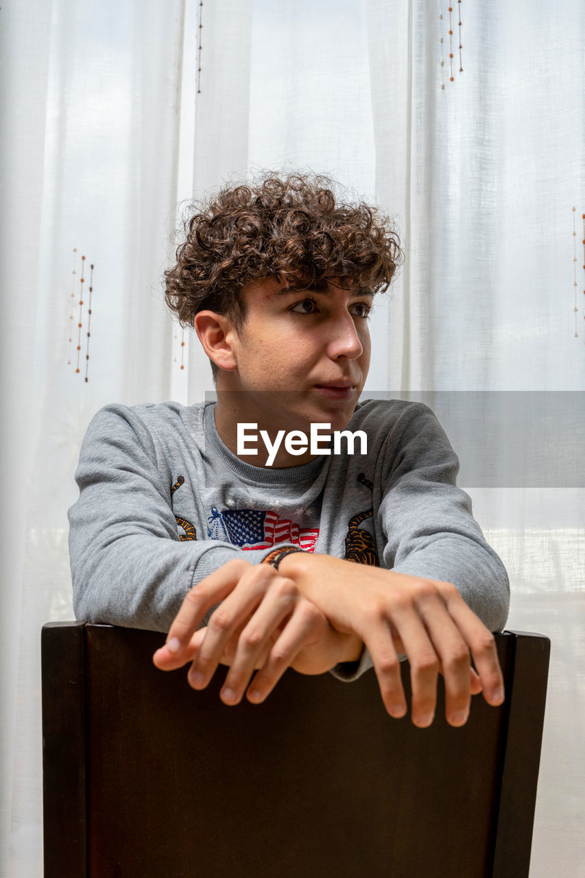 Young man looking away while sitting on seat