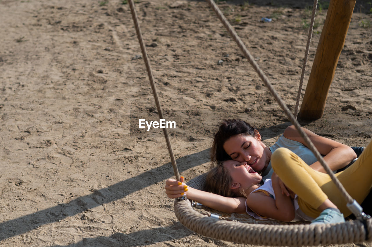 High angle view of mother and daughter embracing on swing