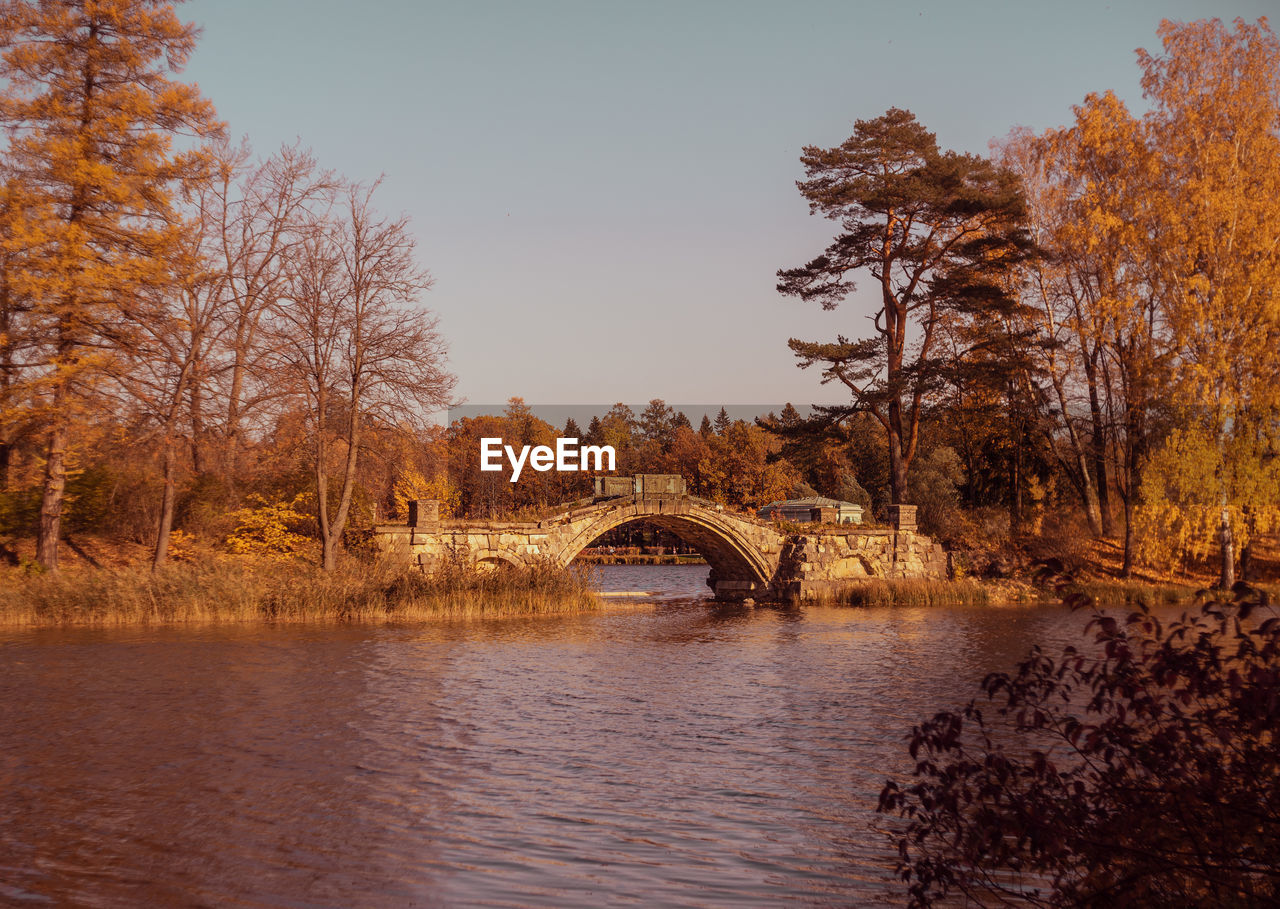 ARCH BRIDGE OVER RIVER BY TREES AGAINST SKY