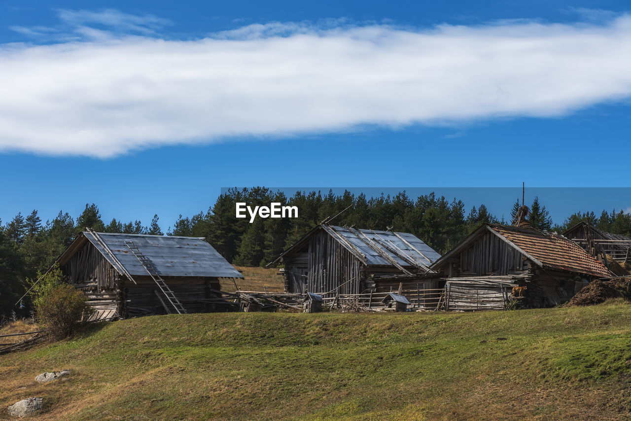 HOUSES ON FIELD AGAINST BLUE SKY