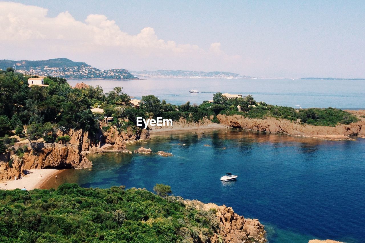 Scenic view of sea by mountain against sky