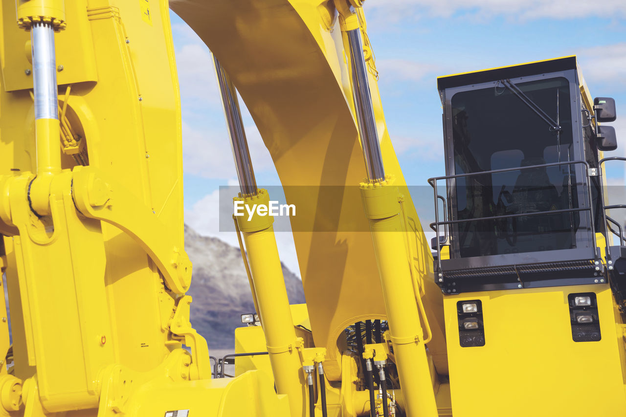 Low angle view of yellow machinery against sky