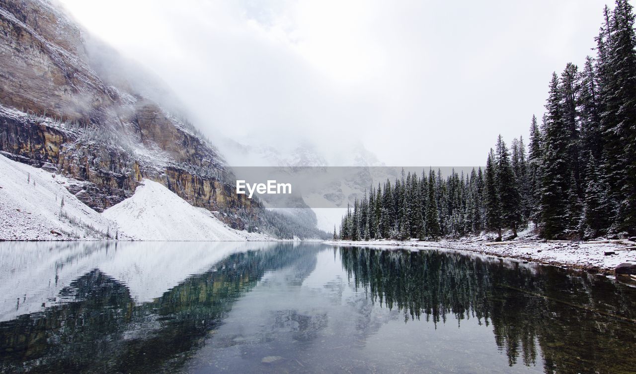 Scenic view of lake by trees and mountains against sky