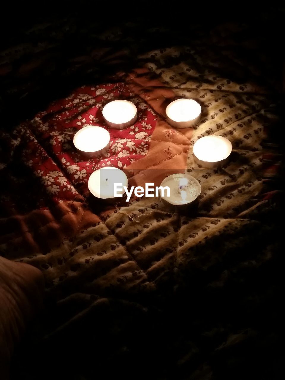 High angle view of lit tea light candles on bed in darkroom