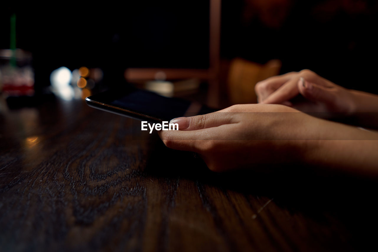 Midsection of person using mobile phone on table