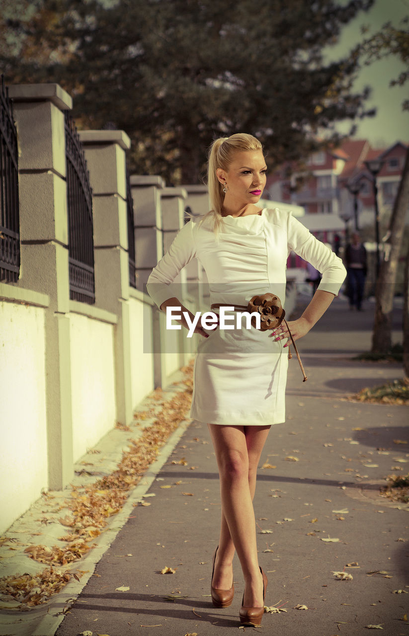 Full length of young woman standing on footpath