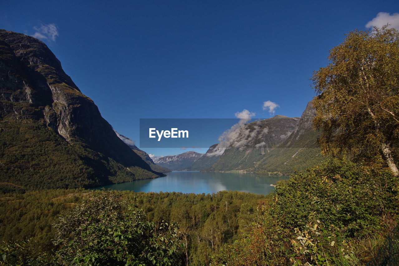 Scenic view of lake and mountains against blue sky