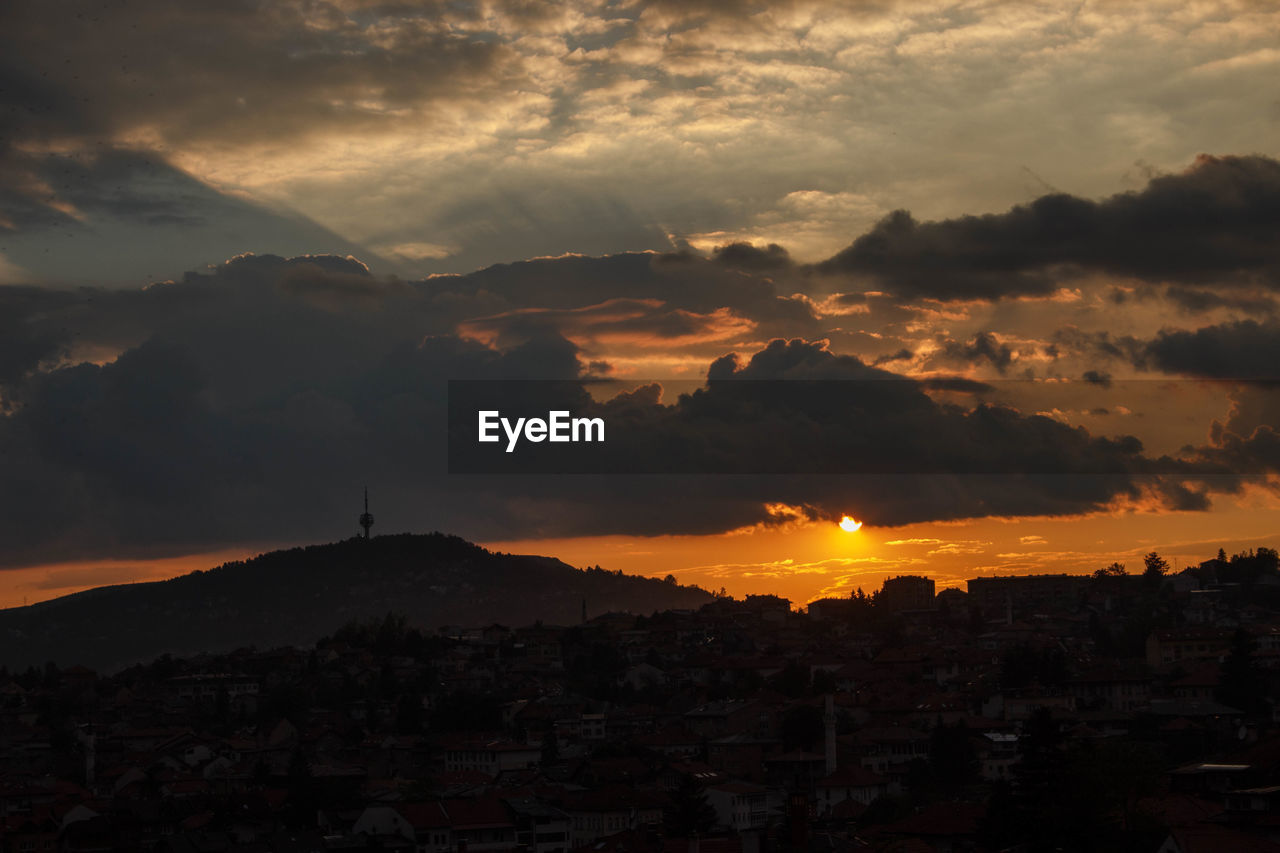 SILHOUETTE BUILDINGS IN CITY AGAINST ORANGE SKY