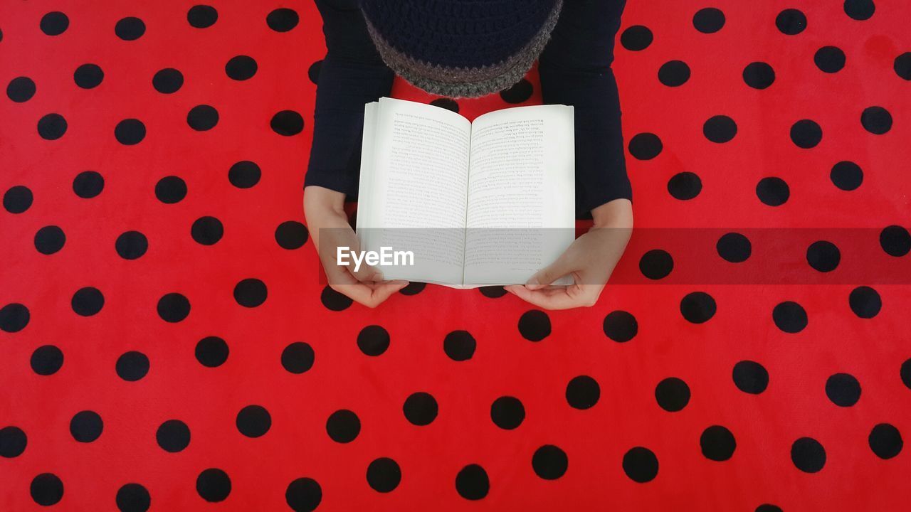 High angle view of person with book on red blanket