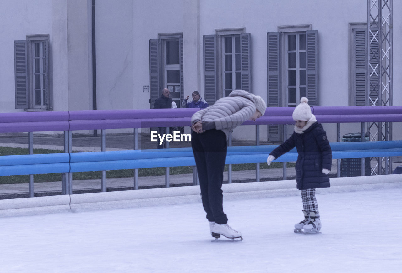 REAR VIEW OF PEOPLE STANDING ON SNOW