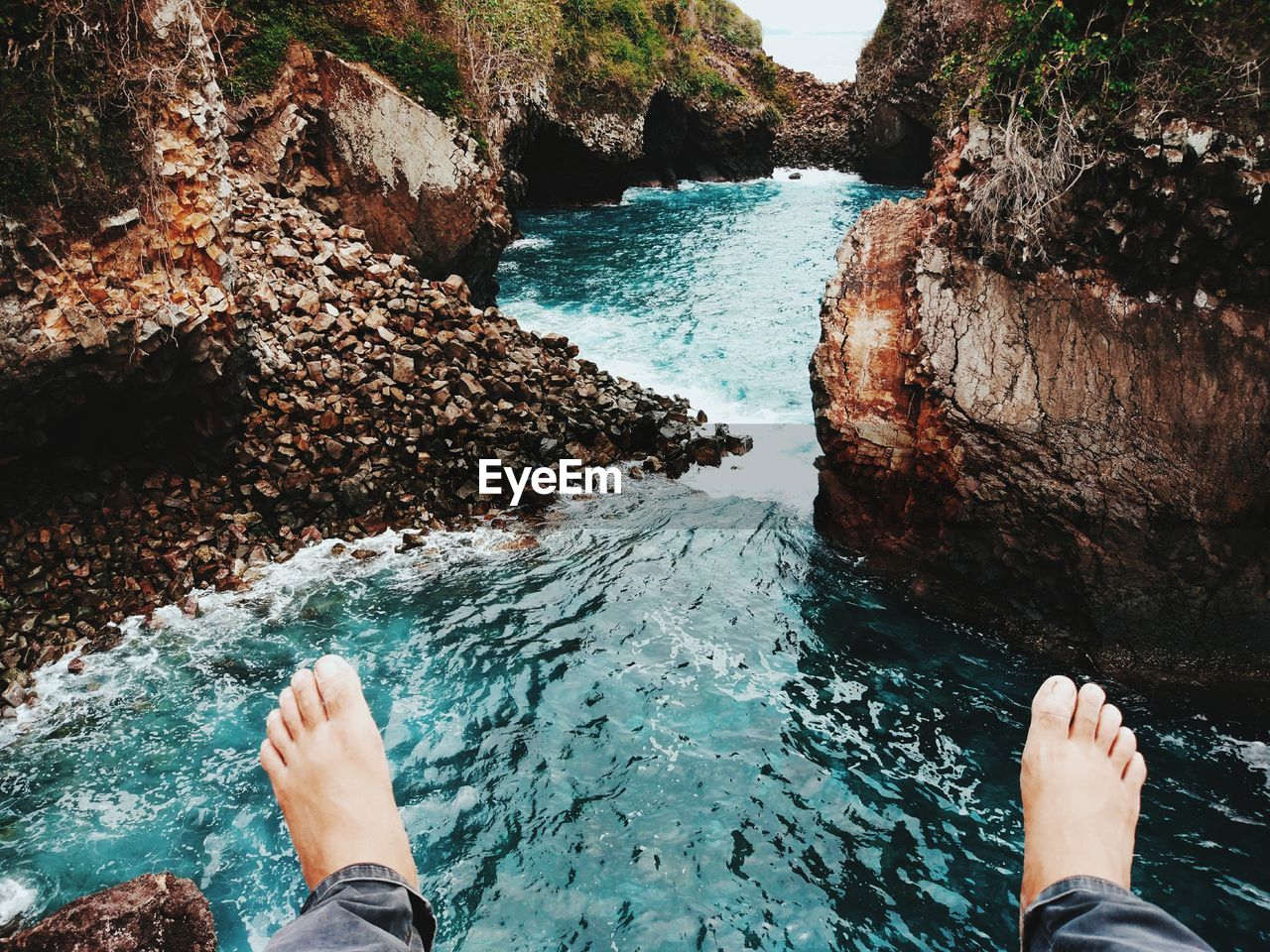 Low section of man over flowing river amidst rocks