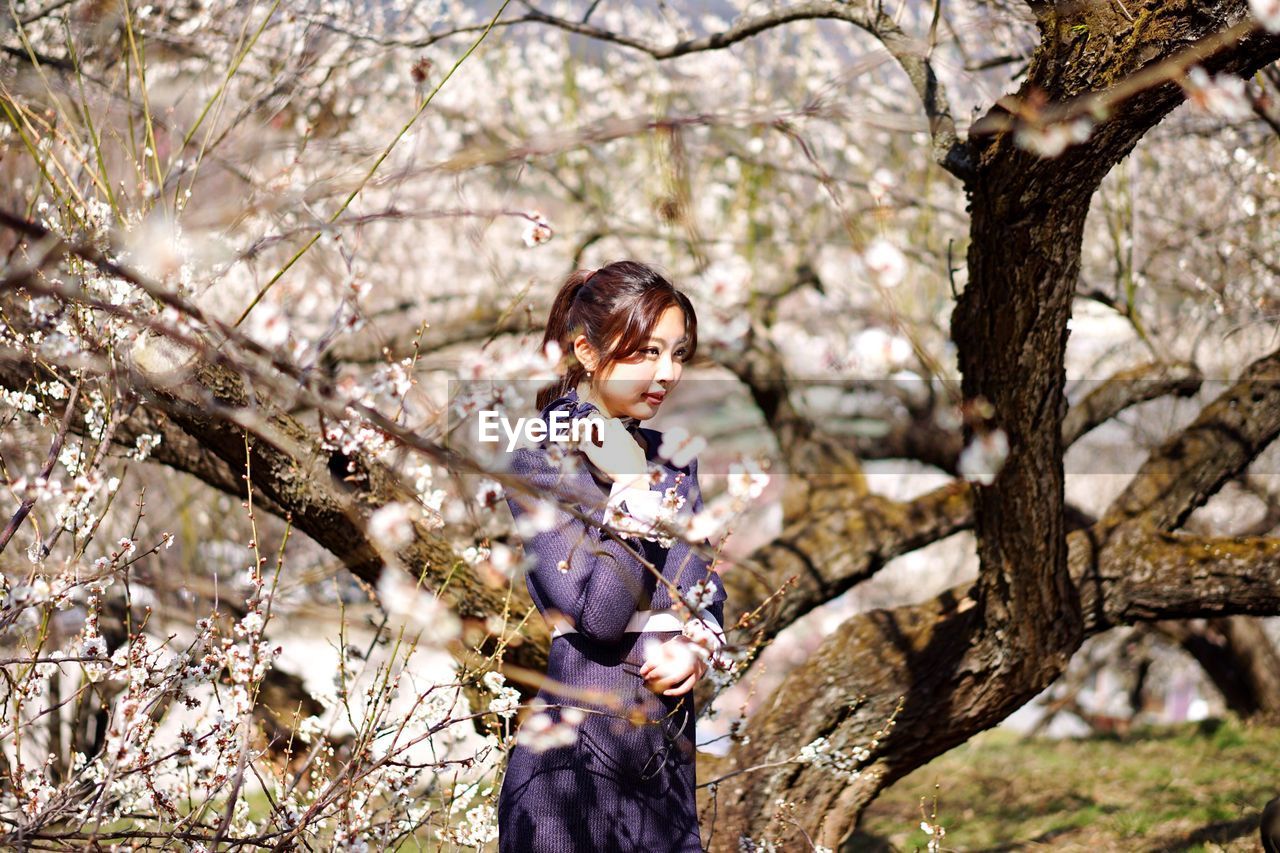 WOMAN STANDING ON TREE TRUNK