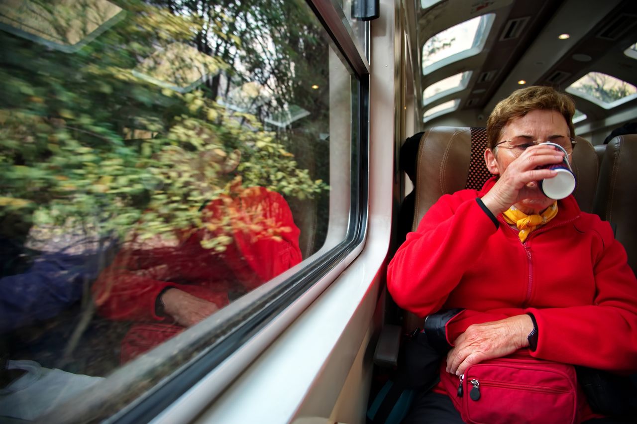 Senior woman traveling by train. reflection in the window