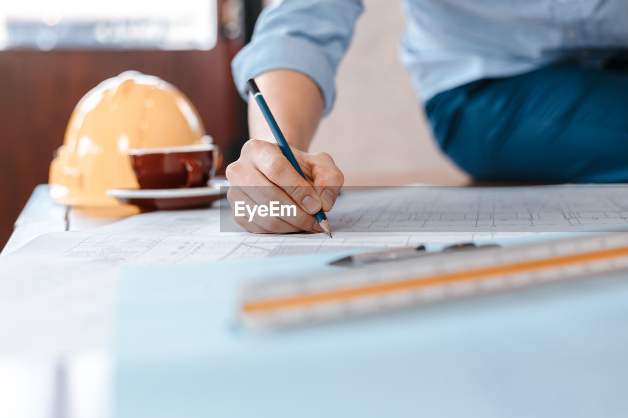 MIDSECTION OF WOMAN WORKING ON TABLE WITH PAPER