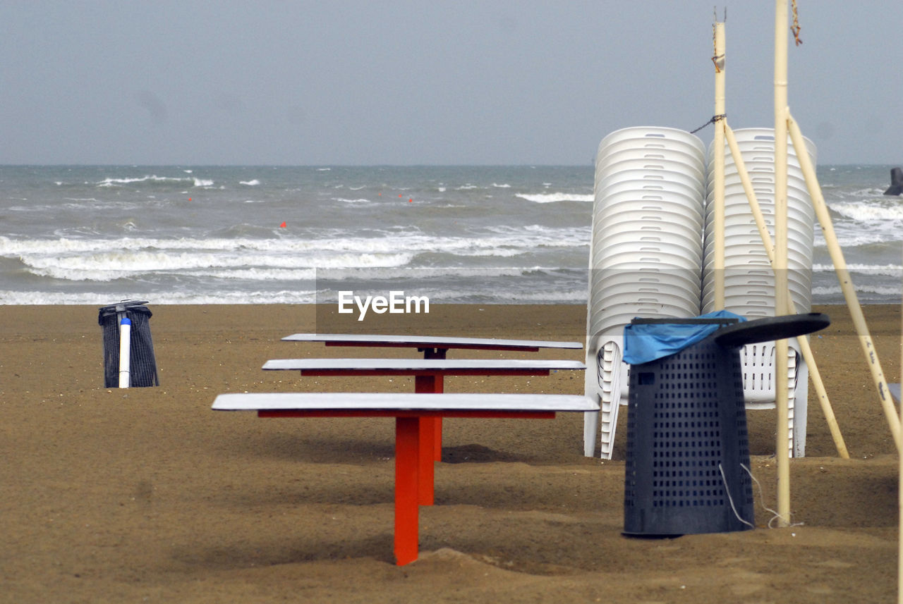 LOUNGE CHAIRS ON BEACH AGAINST SEA