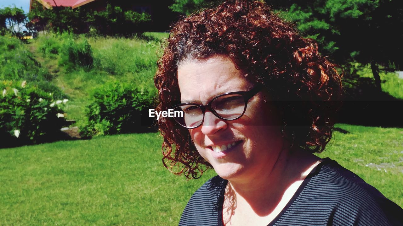 Close-up of woman with curly hair wearing eyeglasses on sunny day