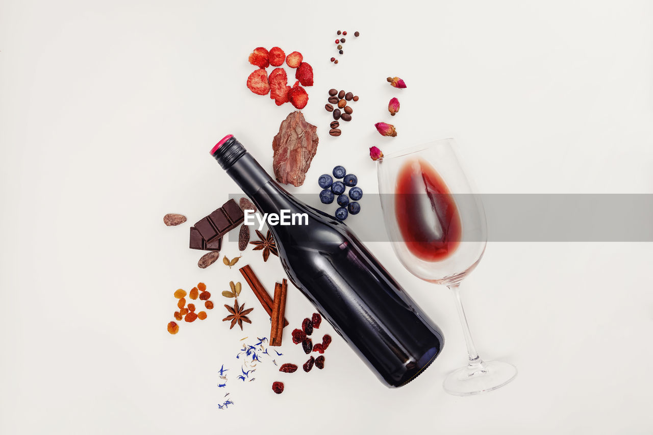 Creative composition with wine bottle, glass and possible flavor components of red wine.