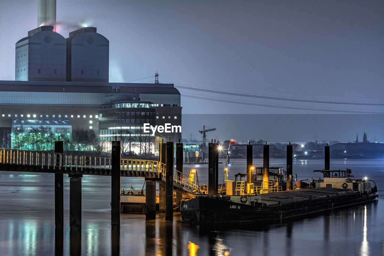 Boat moored at harbor in city at dusk