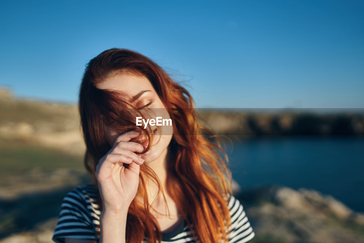 PORTRAIT OF YOUNG WOMAN AGAINST SKY DURING SUNSET