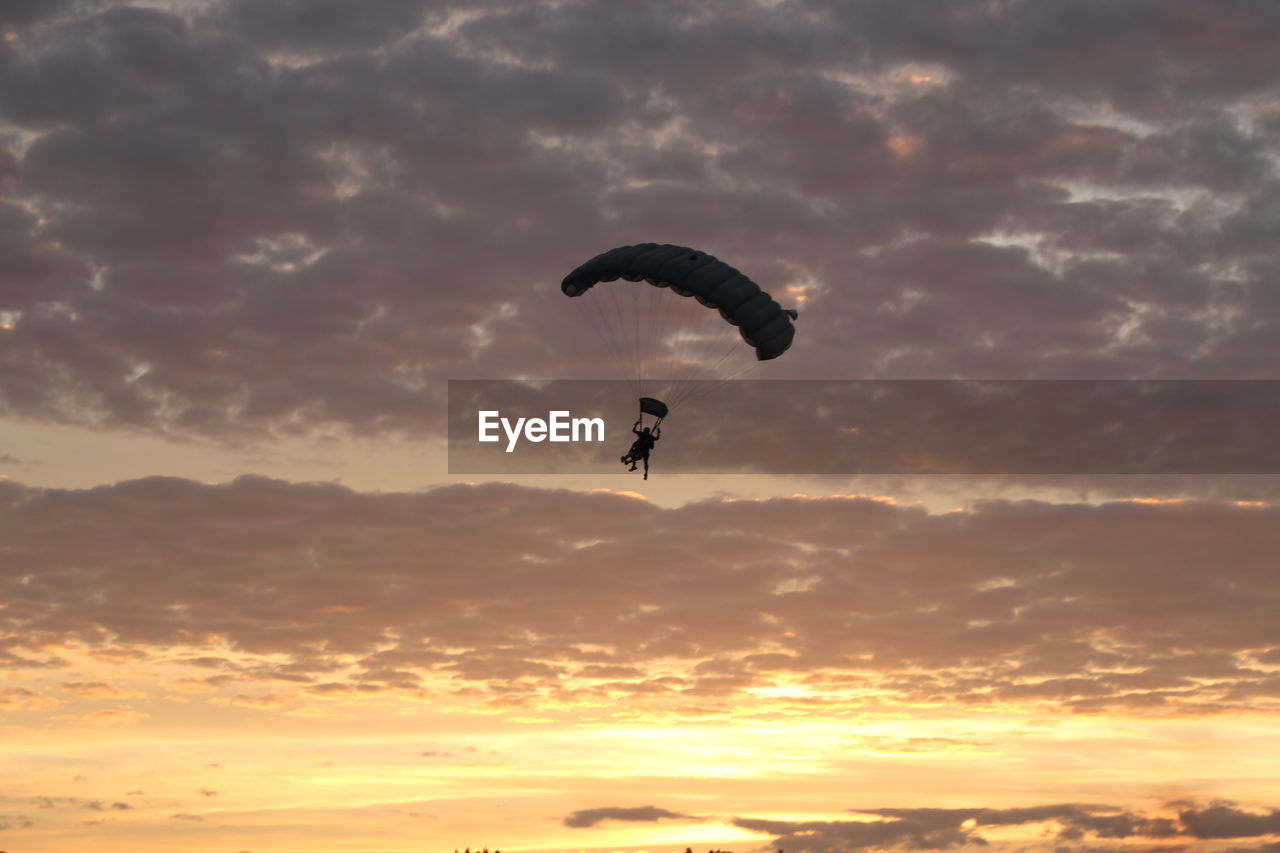 LOW ANGLE VIEW OF SILHOUETTE PARAGLIDING AGAINST SKY