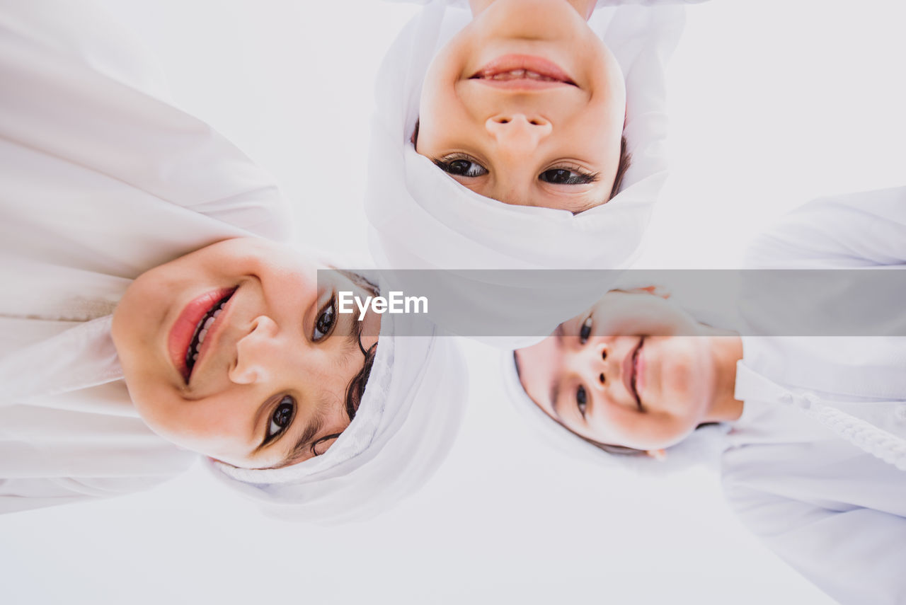 Low angle portrait of cute brothers wearing traditional clothing against clear sky