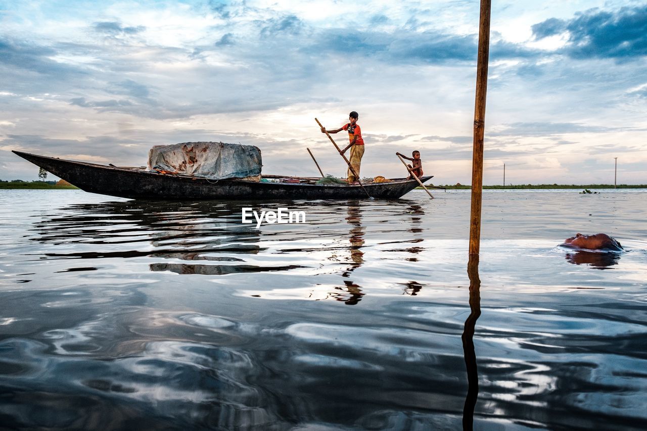 MAN FISHING IN SEA AGAINST SKY