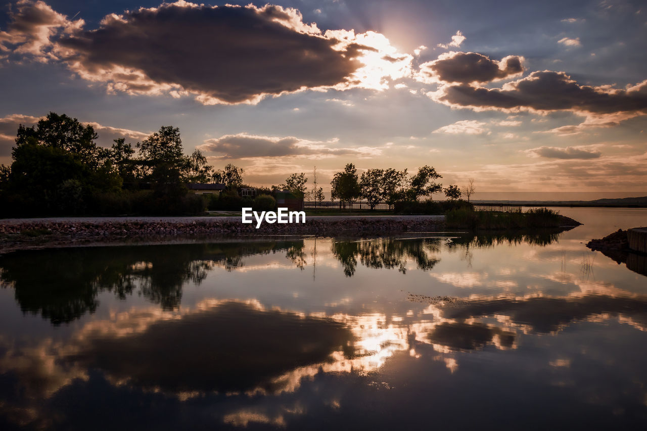 REFLECTION OF TREES IN LAKE DURING SUNSET