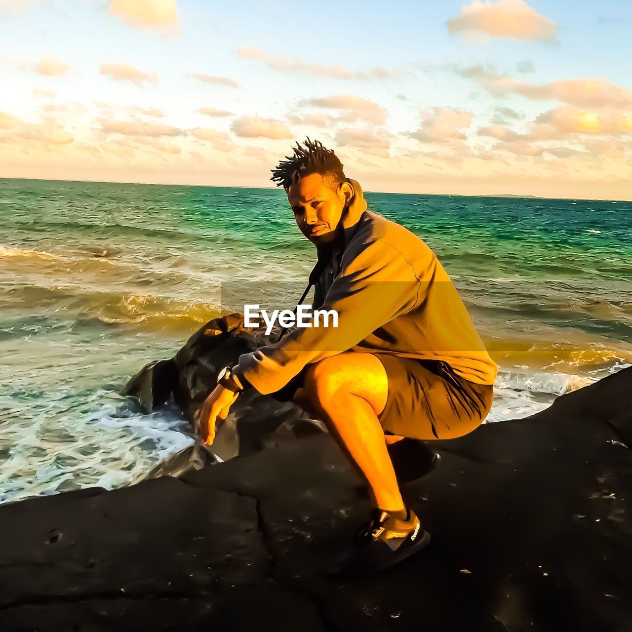 YOUNG MAN STANDING ON BEACH AGAINST SKY