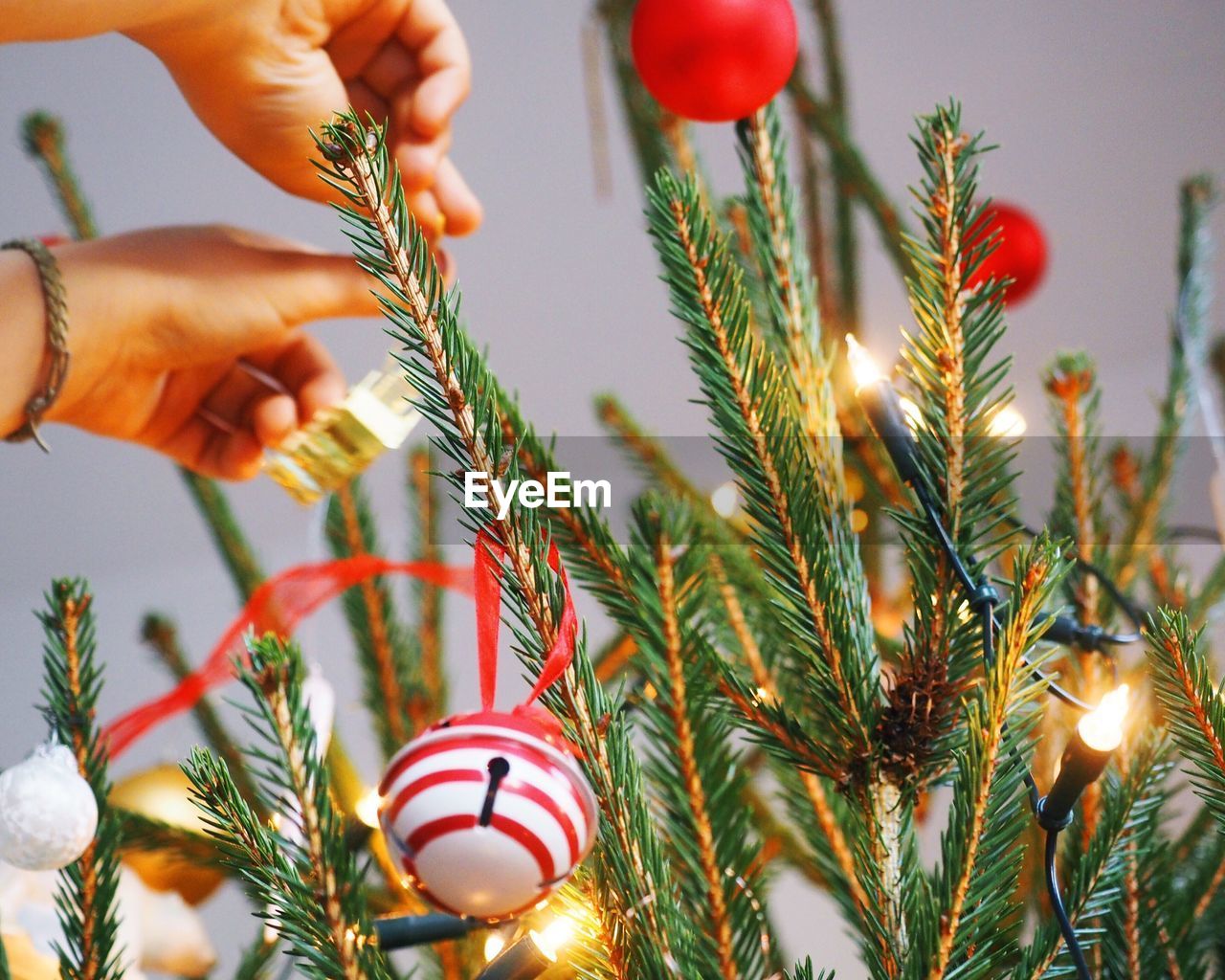 Cropped hands decorating christmas tree