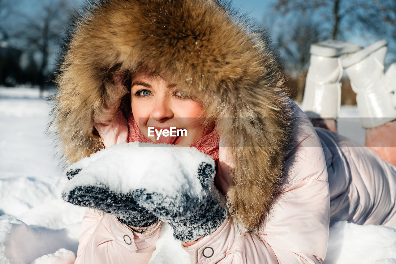 PORTRAIT OF SMILING WOMAN WITH ICE CREAM IN SNOW