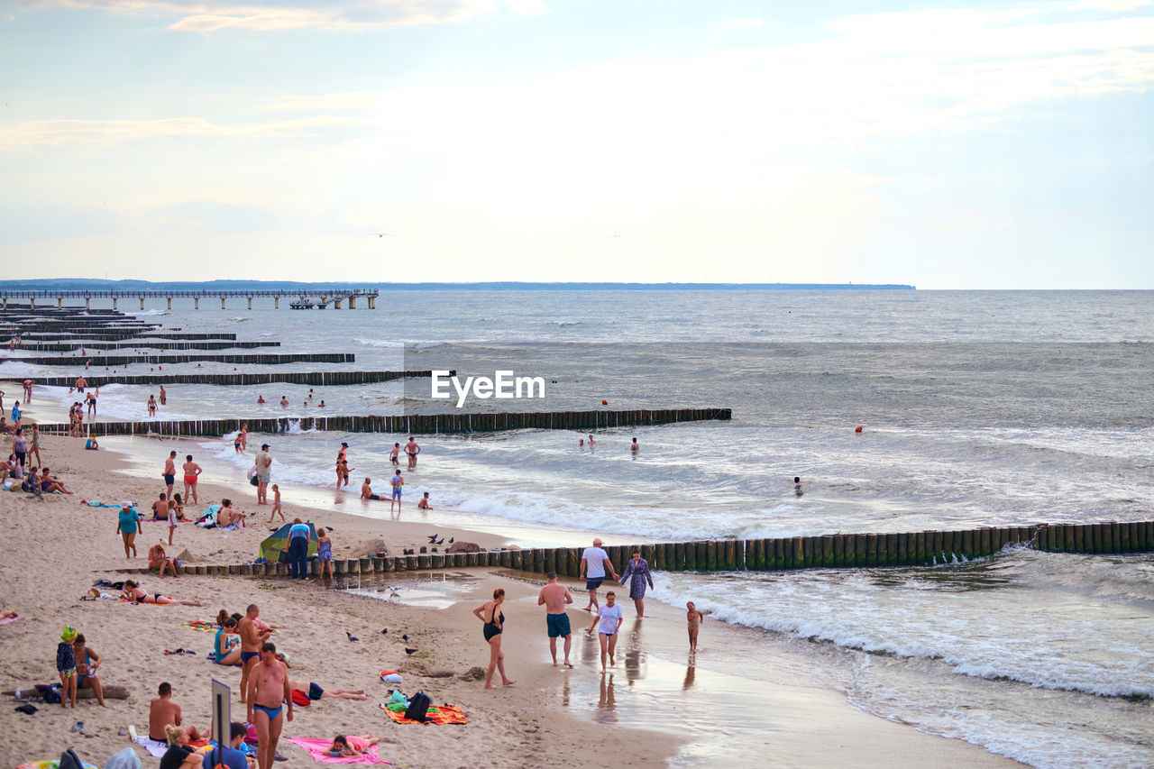 GROUP OF PEOPLE ON BEACH AGAINST SKY