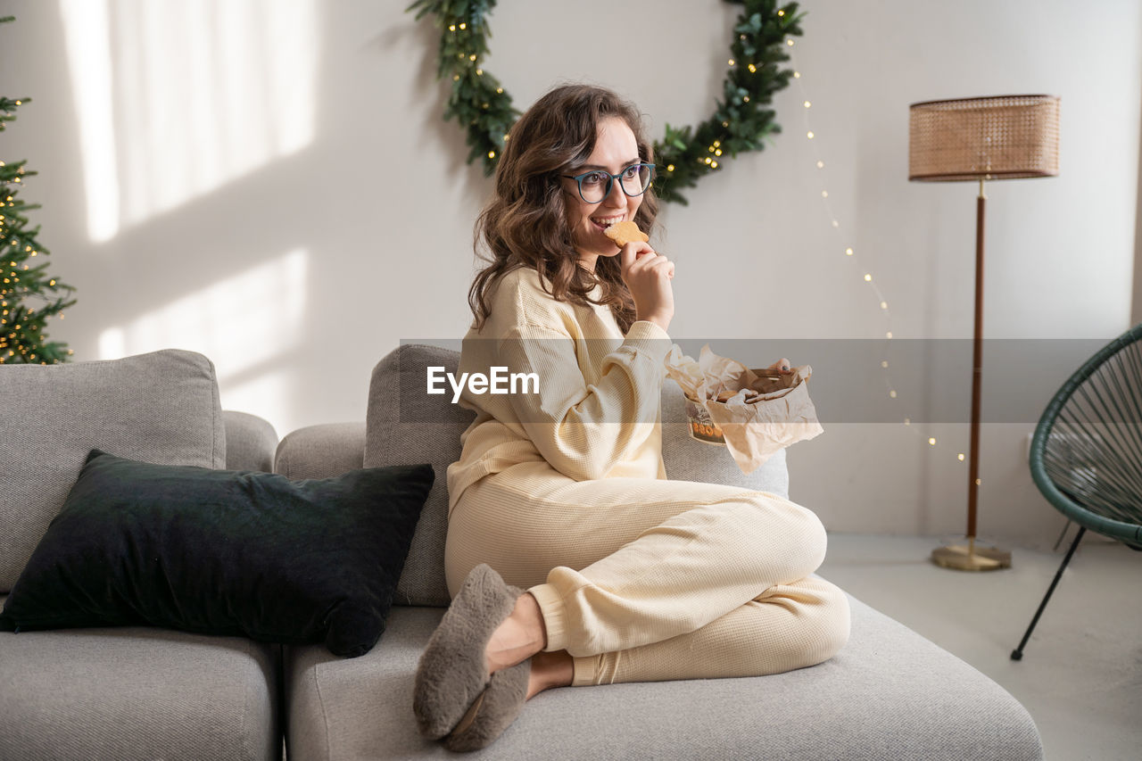 Side view of woman sitting on bed at home