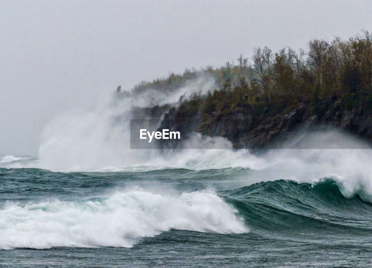 SCENIC VIEW OF WAVES BREAKING AGAINST SKY