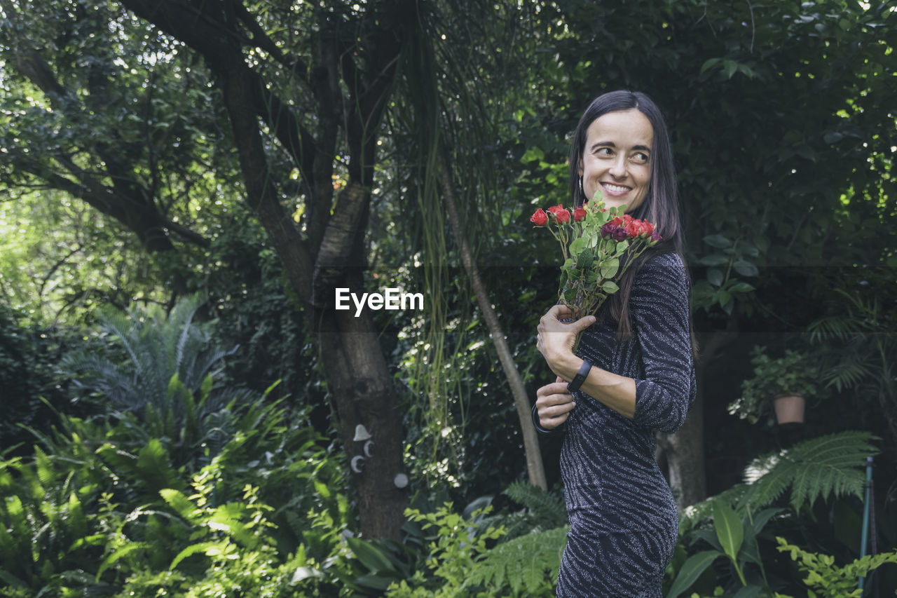 Beautiful woman posing in her garden., while holding flowers