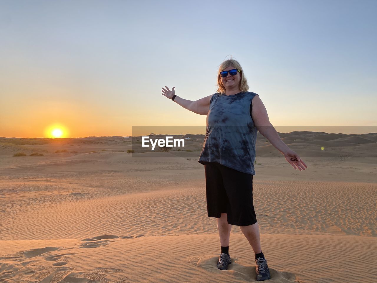 Full length of woman standing in desert against sky during sunset
