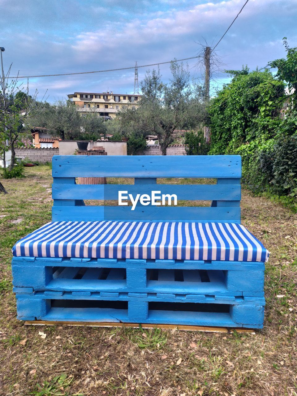 EMPTY BENCH ON FIELD AGAINST BLUE SKY