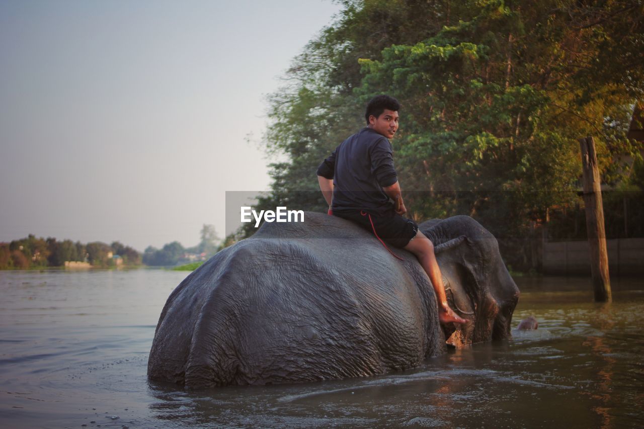 MAN SITTING ON RIVERBANK BY RIVER