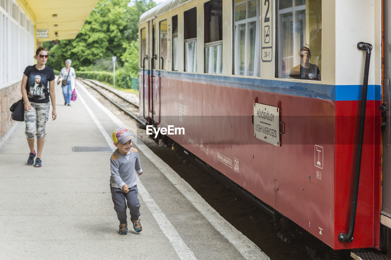 Happy son with mother walking on railroad station platform