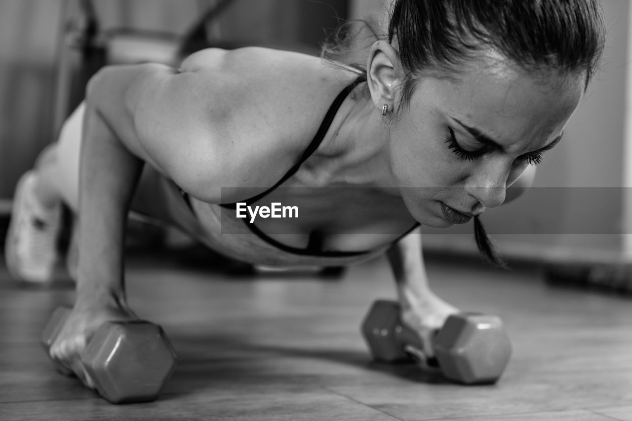 Woman doing push ups with barbells in gym